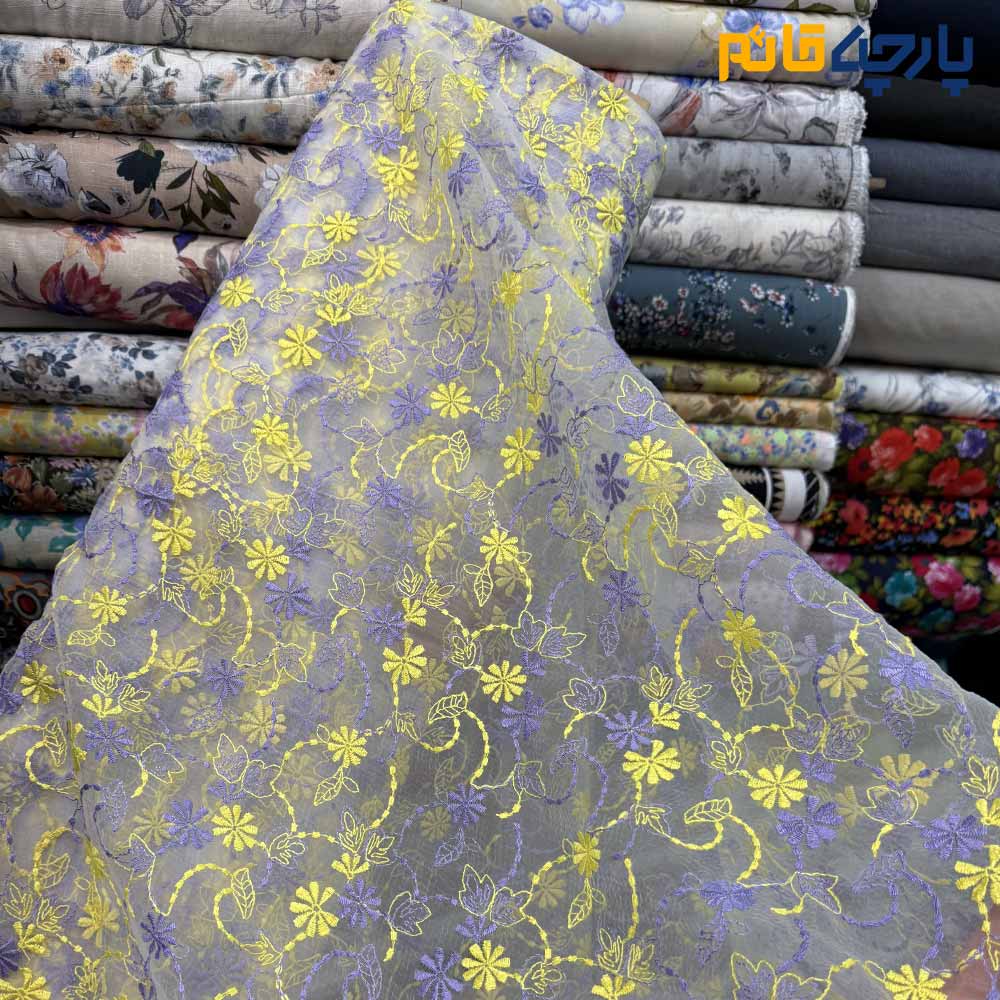 پارچه مجلسی تور کتان طرح گل متوسط زمینه اورگاندی رنگ زرد و بنفش