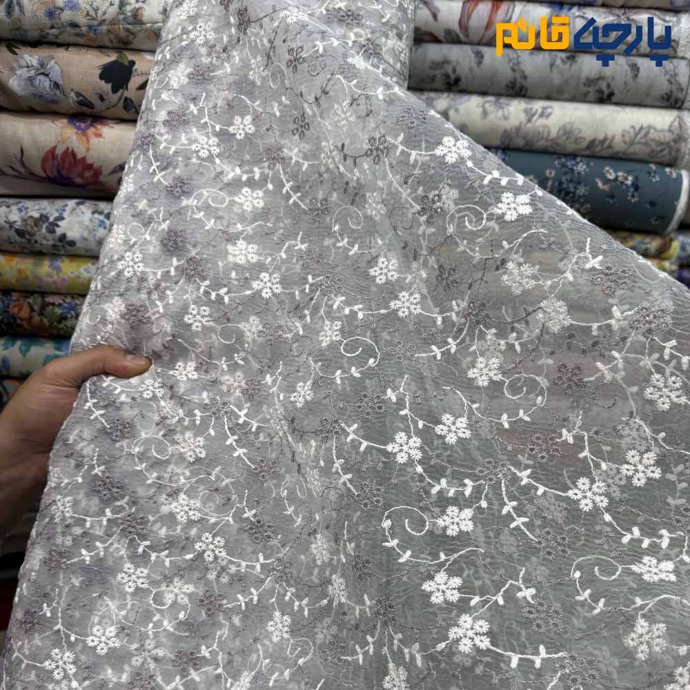 پارچه مجلسی تور کتان طرح گل متوسط و شاخه رنگ طوسی روشن و سفید زمینه اورگاندی