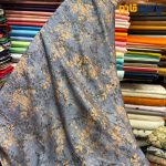 پارچه بهاره تابستانه سیلک نخ طرحدار زمینه رنگ آبی نفتی طرح شاخه و برگ ریز