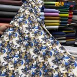 پارچه مجلسی سیلک ابریشم طرحدار زمینه سفید کرم روشن گل درشت آبی شاد